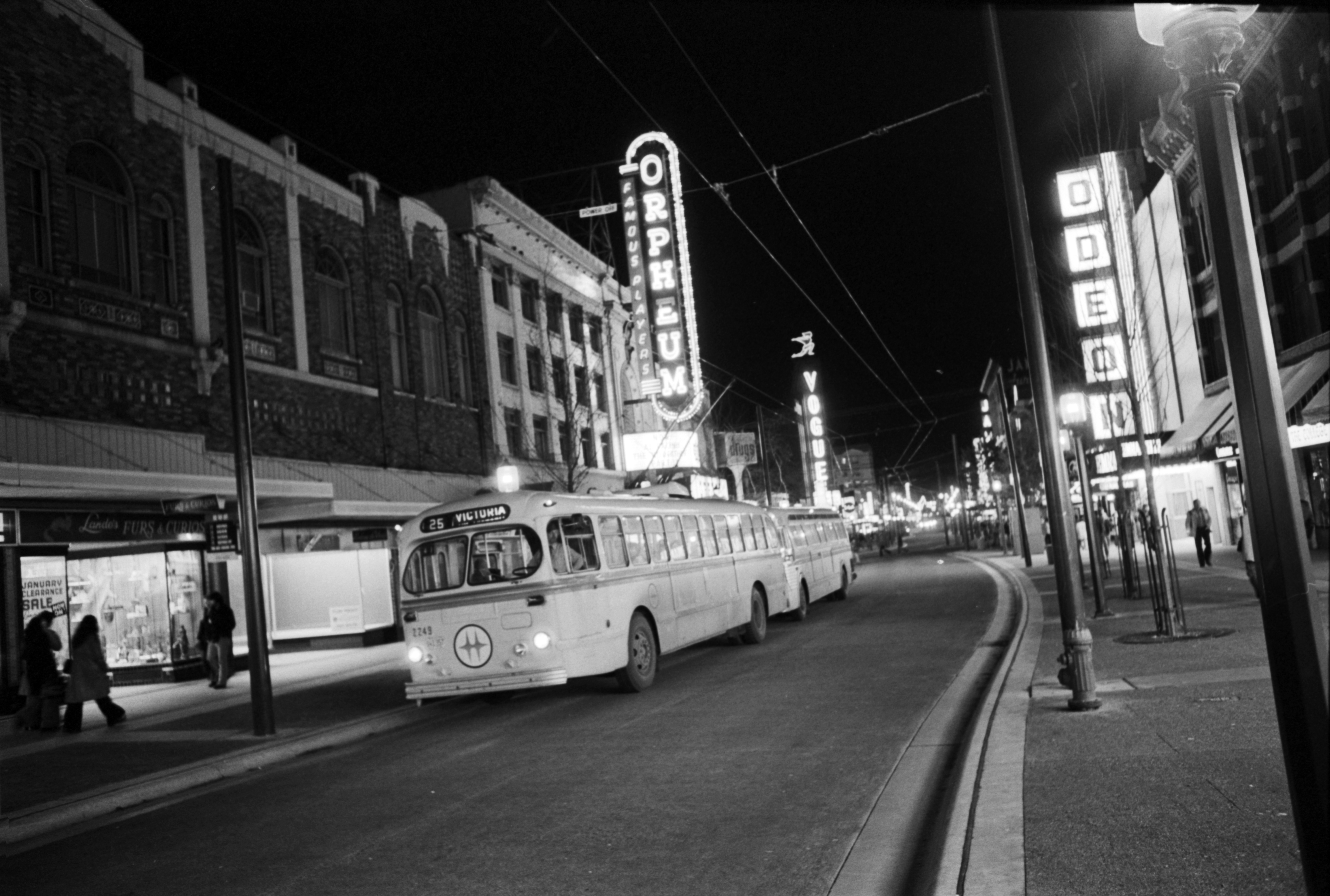 With electric trolley buses and neon signs as a backdrop, Granville Street glows at night. January 3, 1975. Ralph Bower/Vancouver Sun (75-0026)